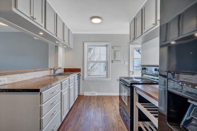 kitchen featuring gray cabinetry, dark wood-type flooring, a sink, baseboards, and black appliances