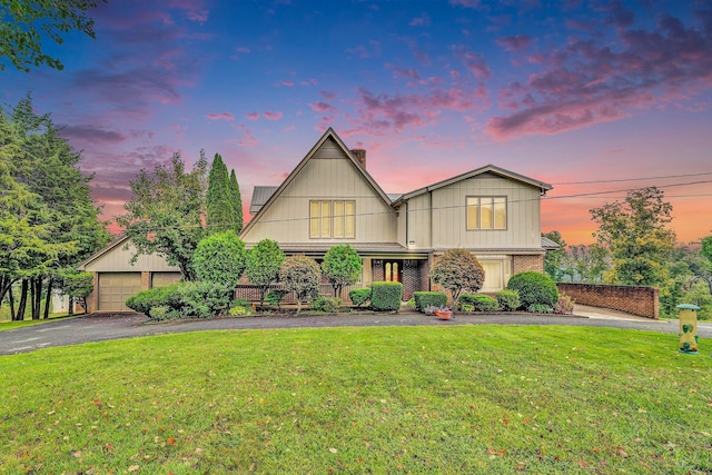 view of front of house with a front yard, brick siding, and a detached garage