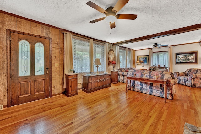 foyer entrance featuring a textured ceiling, crown molding, and light wood-style floors