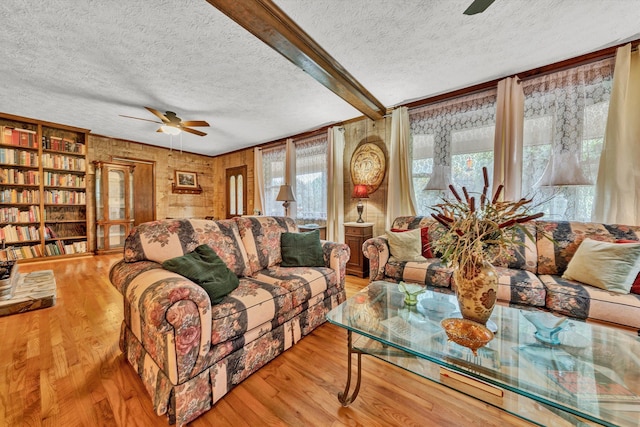 living area with light wood-style flooring, beam ceiling, ceiling fan, and a textured ceiling