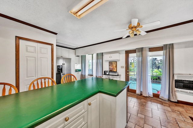 kitchen with white cabinetry, a wealth of natural light, heating unit, dark countertops, and stainless steel fridge