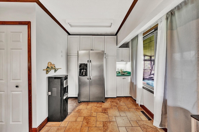 kitchen featuring white cabinetry, baseboards, ornamental molding, stone finish floor, and stainless steel fridge