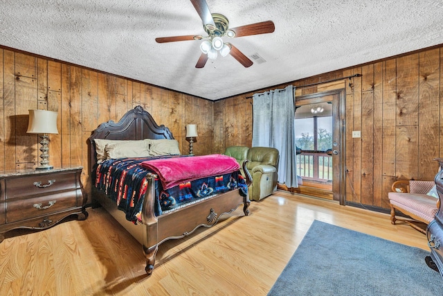 bedroom with visible vents, wood walls, light wood-style flooring, and a textured ceiling