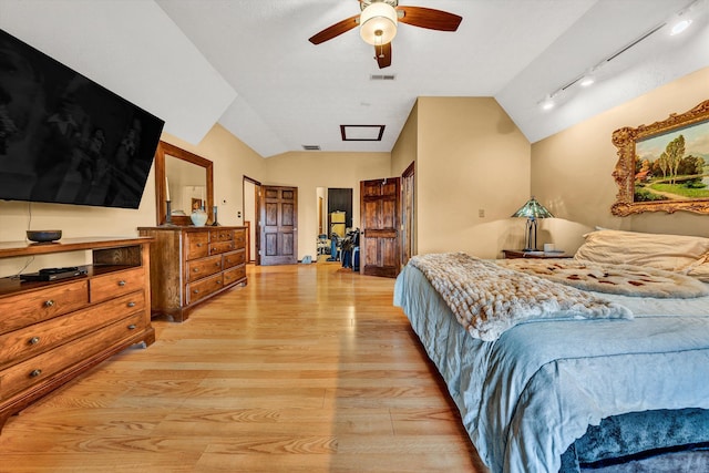 bedroom with light wood-style floors, lofted ceiling, visible vents, and track lighting