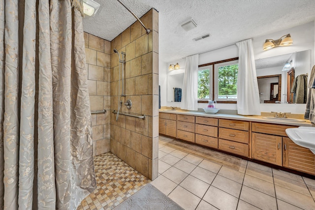 full bath featuring a textured ceiling, a sink, visible vents, tile patterned floors, and a stall shower