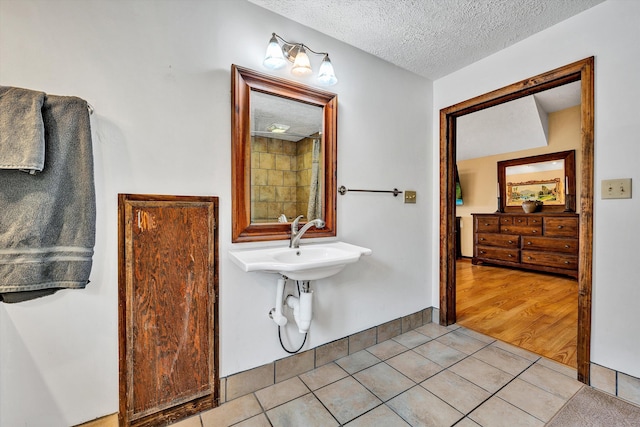 bathroom featuring a textured ceiling, tile patterned flooring, and baseboards