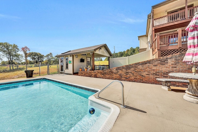 pool with a patio area, fence, an exterior structure, and an outdoor structure