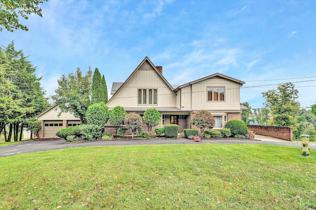 view of front of home with a garage, brick siding, a front lawn, and a chimney