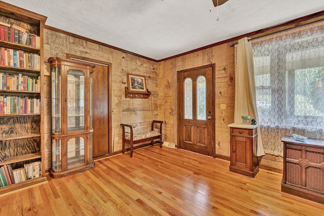 foyer entrance with ornamental molding, a wealth of natural light, light wood-style flooring, and a textured ceiling