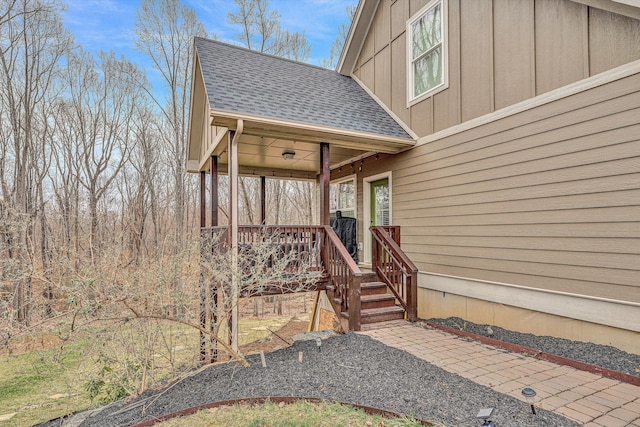 view of exterior entry with a shingled roof and board and batten siding