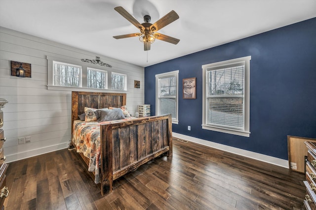 bedroom with dark wood-style floors, multiple windows, and baseboards