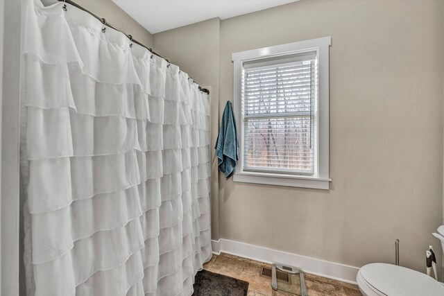 full bath with curtained shower, baseboards, and toilet