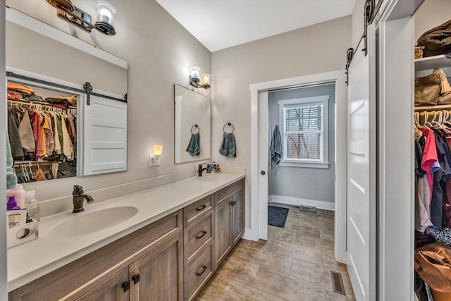 bathroom with double vanity, baseboards, visible vents, and a sink