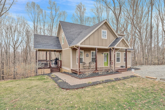 view of front facade with a front lawn, a porch, a shingled roof, and board and batten siding