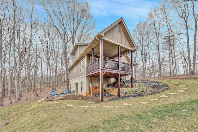 rear view of property featuring board and batten siding, a lawn, and a deck