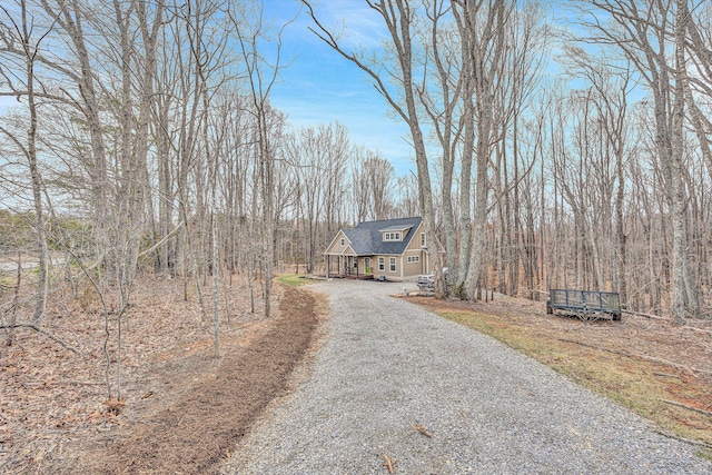 view of front of property featuring a shingled roof and gravel driveway