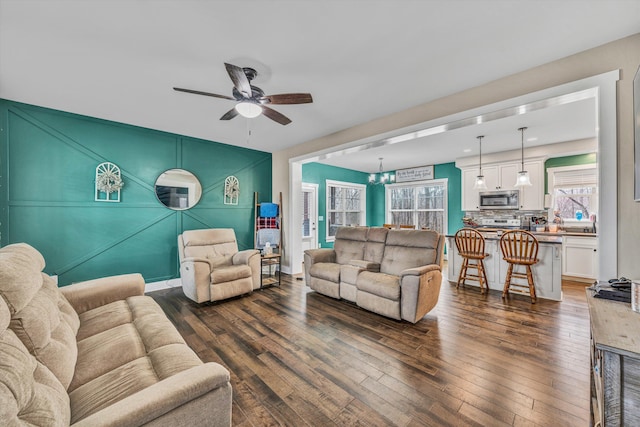 living room featuring dark wood-type flooring, baseboards, and a ceiling fan