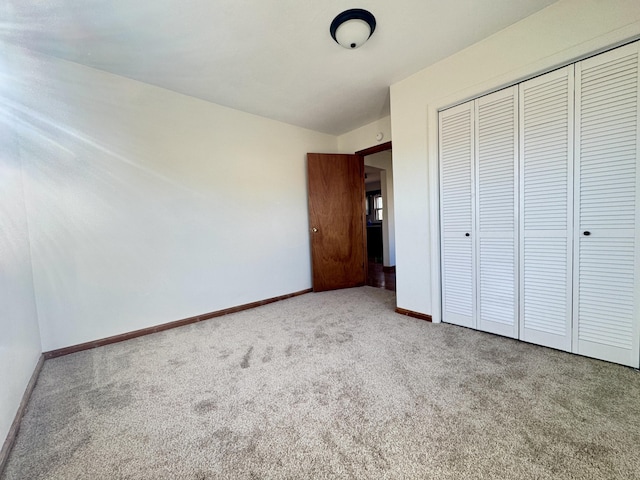 unfurnished bedroom featuring carpet floors, a closet, and baseboards