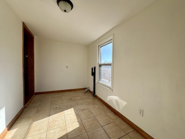 empty room featuring light tile patterned floors and baseboards