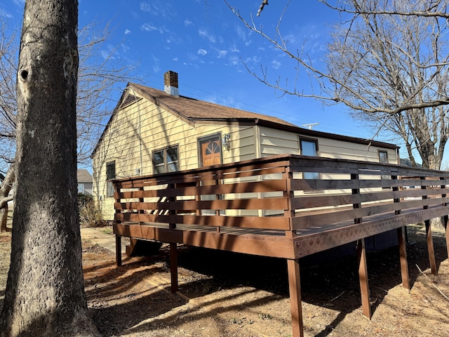 rear view of house with a shingled roof, a chimney, and a wooden deck