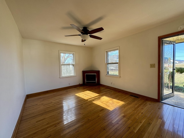 unfurnished living room featuring wood-type flooring, visible vents, and a wealth of natural light