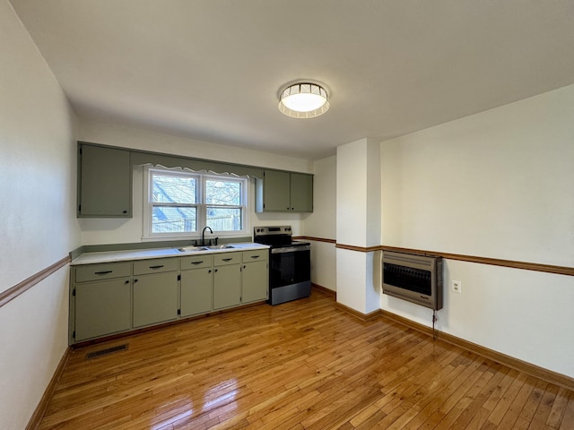 kitchen with heating unit, a sink, light wood finished floors, and stainless steel electric range