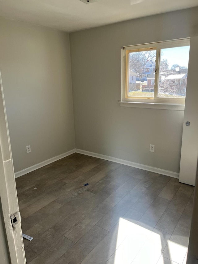 unfurnished room featuring baseboards and dark wood-type flooring