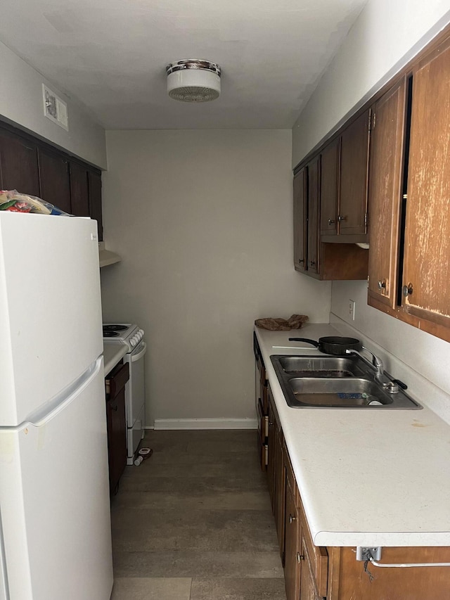 kitchen featuring light countertops, visible vents, a sink, white appliances, and baseboards