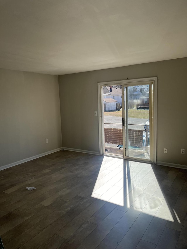 empty room with dark wood-style floors and baseboards