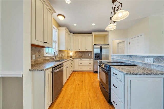 kitchen featuring backsplash, stainless steel appliances, a sink, and light wood finished floors
