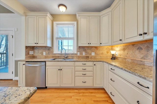 kitchen featuring backsplash, a sink, light stone countertops, light wood-type flooring, and dishwasher