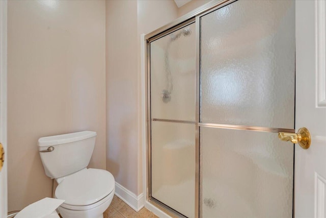 bathroom featuring a stall shower, tile patterned flooring, toilet, and baseboards