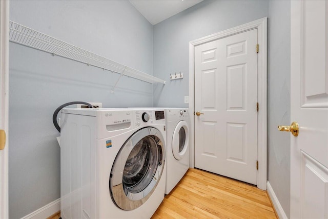 laundry room with light wood-style floors, laundry area, washer and clothes dryer, and baseboards