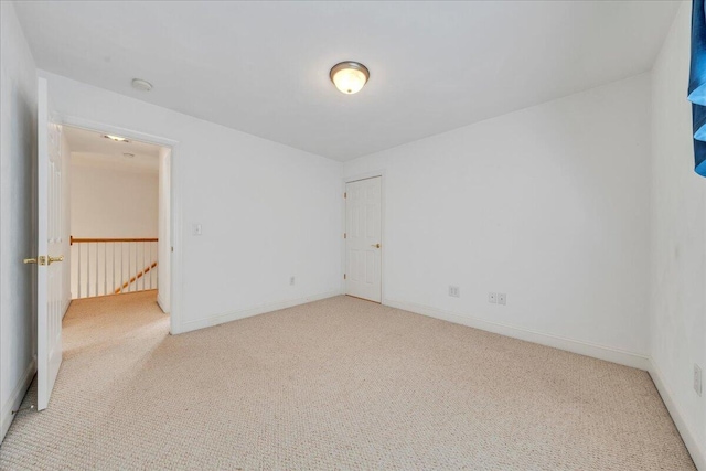 unfurnished room with baseboards and light colored carpet