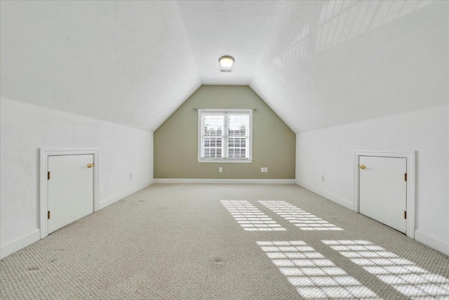 bonus room featuring lofted ceiling, light colored carpet, and baseboards