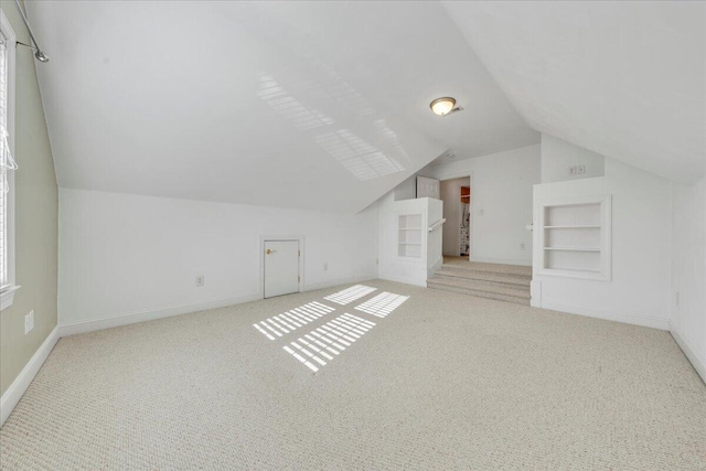 additional living space featuring built in features, a healthy amount of sunlight, carpet floors, and baseboards