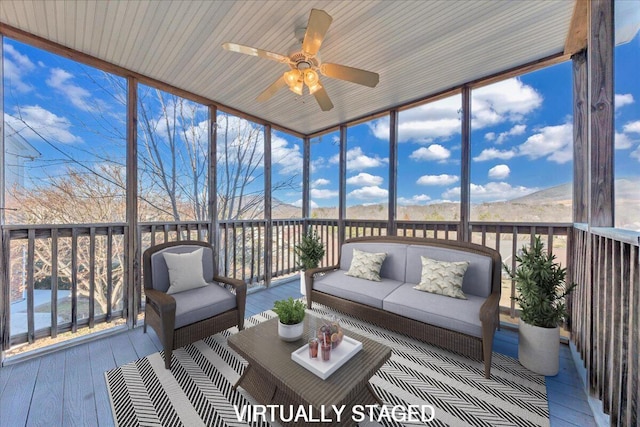 sunroom / solarium featuring a healthy amount of sunlight, ceiling fan, and a mountain view