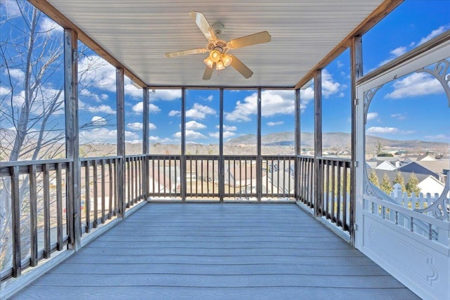 unfurnished sunroom with ceiling fan and a mountain view