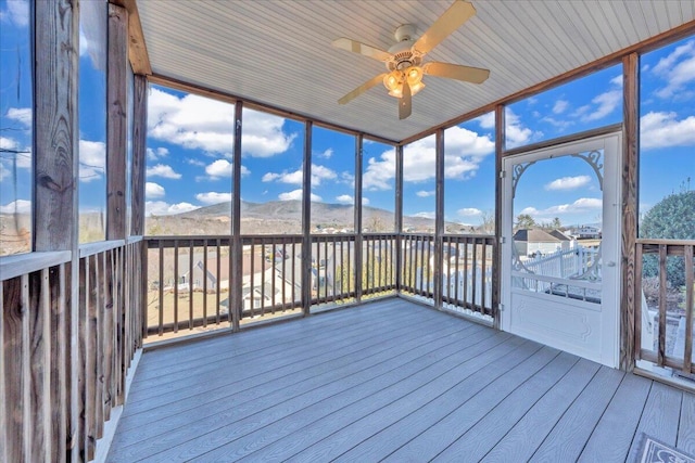 unfurnished sunroom featuring a mountain view and ceiling fan