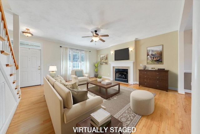 living area featuring light wood-type flooring, stairway, crown molding, and a tile fireplace