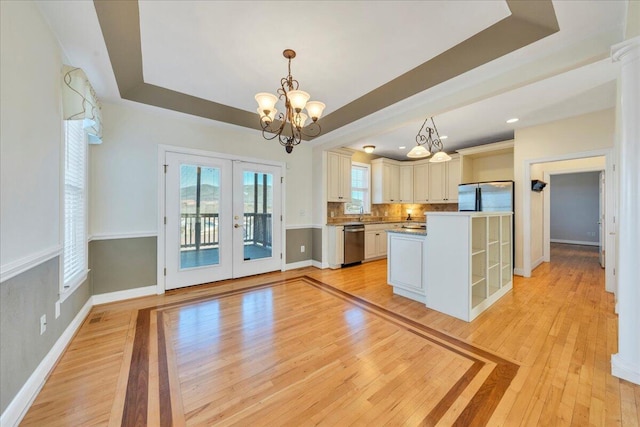 kitchen featuring refrigerator, french doors, dishwasher, light wood finished floors, and a raised ceiling