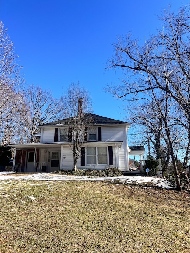 traditional-style home featuring a chimney and a front lawn