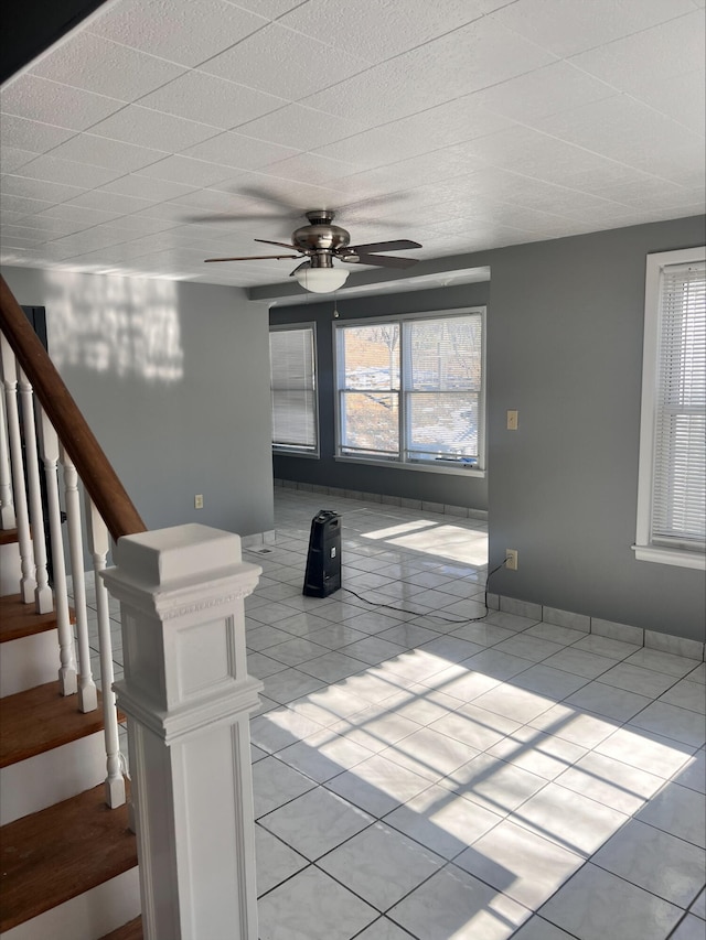 empty room with ceiling fan, stairway, and light tile patterned floors