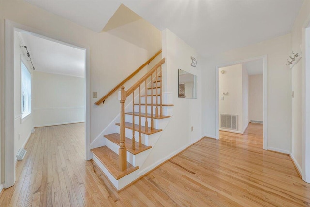 staircase featuring visible vents, baseboards, and wood finished floors