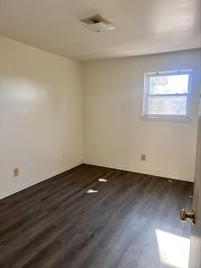 empty room featuring dark wood-style floors and baseboards