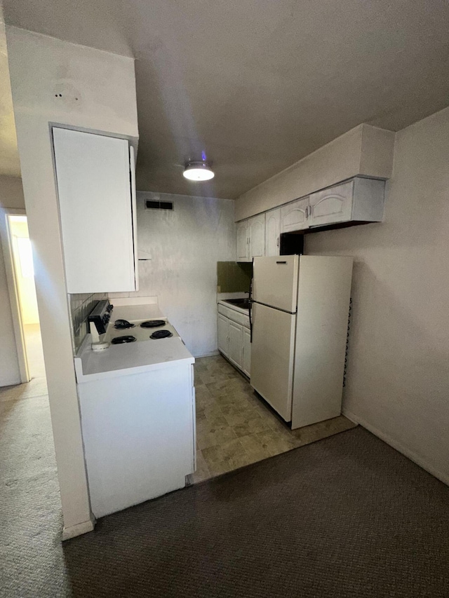 kitchen featuring light countertops, freestanding refrigerator, white cabinets, and light colored carpet