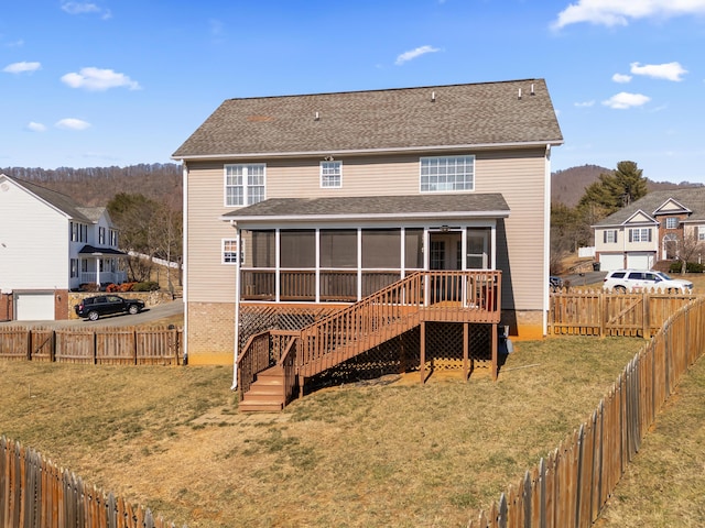 rear view of house featuring stairs, a yard, a fenced backyard, and a sunroom