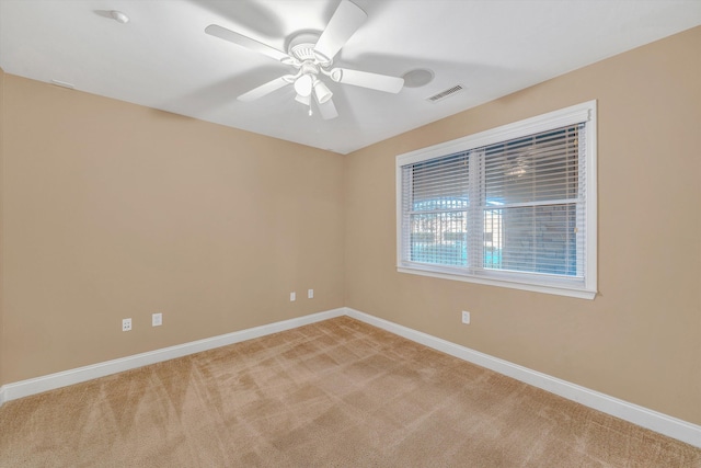 spare room featuring baseboards, visible vents, ceiling fan, and light colored carpet