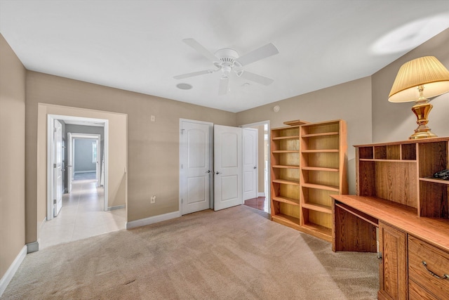 unfurnished office featuring baseboards, a ceiling fan, and light colored carpet