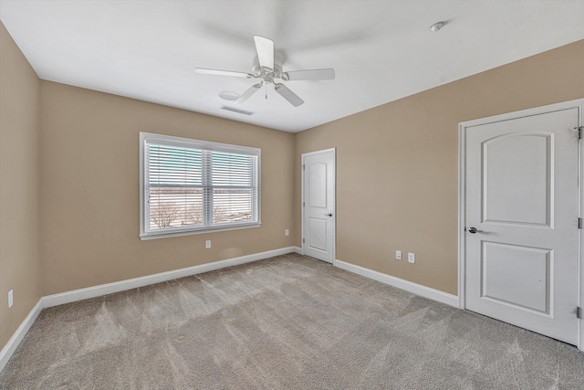 spare room featuring light colored carpet, visible vents, and baseboards